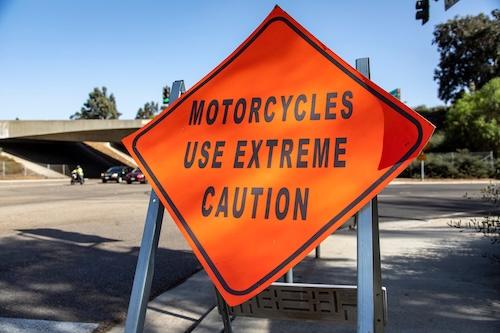 A diamond shaped road sign advising motorcycle riders to use extreme caution