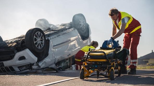 Paramedics and Firefighters Arrive On the Car Crash Traffic Accident Scene. Professionals Preparing Stretchers For Rescue Injured Victim Trapped in Rollover Vehicle.
