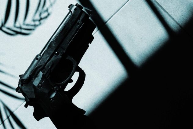 gun laying on the ground in the shadow of a window