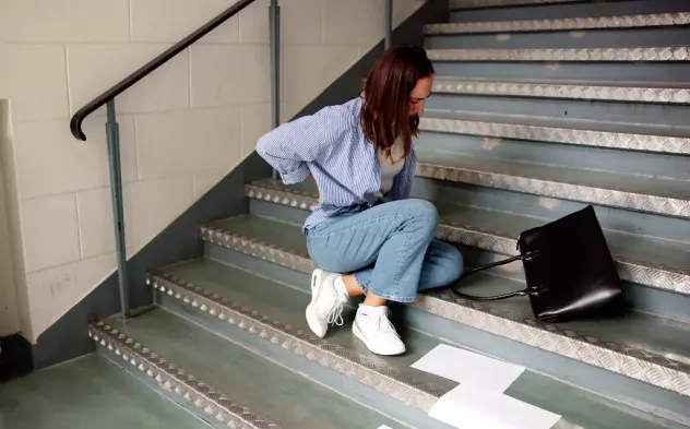 woman holding her back after a slip and fall on stairs